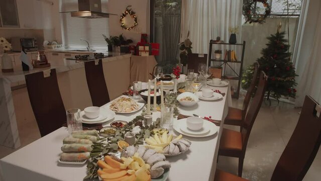 Pan shot of big festive table prepared for Christmas celebration in cozy flat