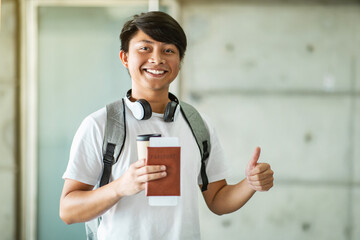 Happy excited young asian man holding passport, showing thumb up