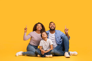 Happy Black Family Of Three Pointing Up At Copy Space Above Heads