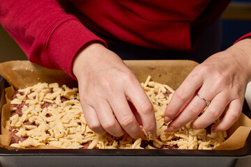 The hands of a woman preparing a traditional homemade dough cake in the kitchen.