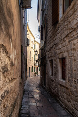 Fototapeta na wymiar Morning walk along winding narrow streets with ancient stone buildings in the old town of Kotor, Montenegro