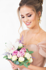 Young pretty bride with bridal bouquet indoors