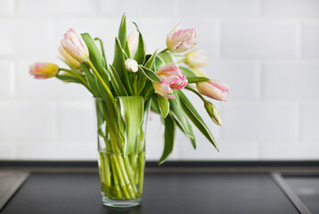 Pink tulips bouquet in glass vase on the kitchen