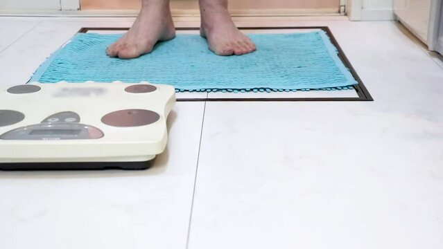 浴室から出て脱衣所で体重を測定する男性