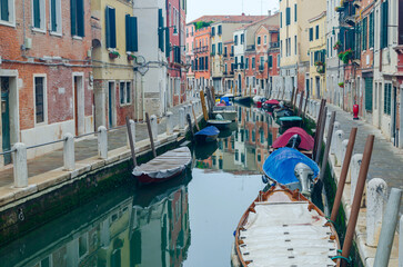 Fototapeta na wymiar Canal in Venice, Italy with parked boats and pedestrian area in a residential part of the city