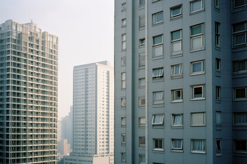 Obraz premium Modern Urban Skyline: A Contemporary High-Rise Apartment Building with Blue Balconies and a Vibrant Cityscape Background