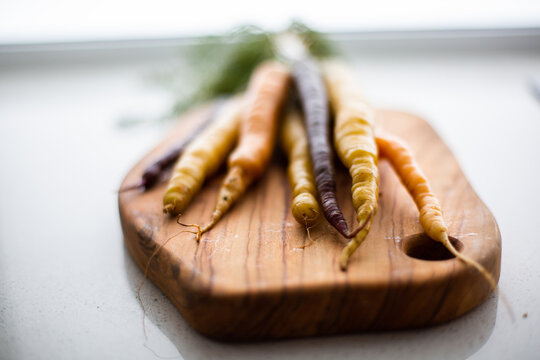 close up of carrot tips on a wooden chopping board