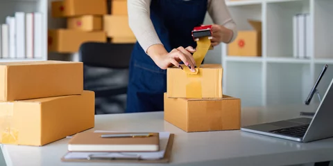 Foto op Plexiglas Woman use scotch tape to attach parcel box to prepare goods for the process of packaging, shipping, online sale internet marketing ecommerce concept startup business idea © Natee Meepian