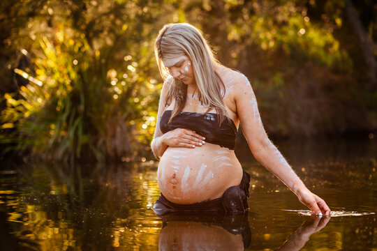 Peaceful scene with pregnant aboriginal woman in still water with reflection