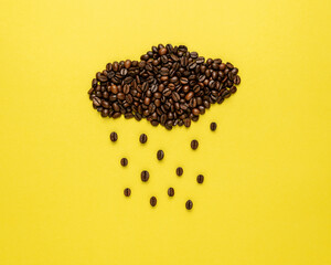 Coffee beans in shape of rainy cloud on yellow background. Creative minimal coffee drink concept.