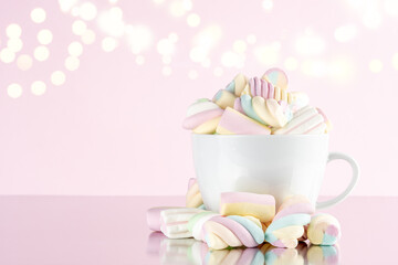 Marshmallows colorful chewy candy in a cup on pink bokeh background. Sweet holiday food concept.