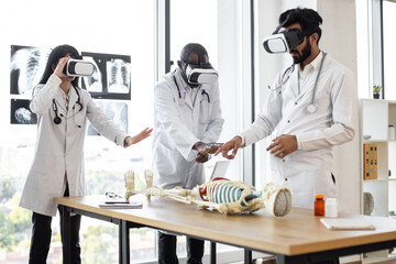 Young multiethnic doctors, bioengeneers, scientists with virtual reality equipment vr goggles in...