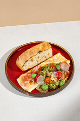 Salmon Omelette with Avocado Mousse and Ciabatta Bread on Reddish Plate.
