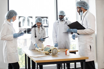 Professional middle aged Indian female doctor, anatomy teacher, explaining bones anatomy using...