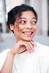 Young beautiful smiling hipster woman in trendy summer white t-shirt and jeans clothes. Carefree woman, posing in the street at sunny day. Positive model outdoors. Cheerful and happy. Closeup