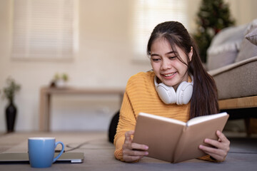 Young pretty woman laying down on floor and reading a book enjoys of rest. relaxing at home