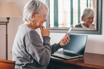 Elderly grandmother using smartphone apps, senior gray-haired woman enjoy online entertainments,...