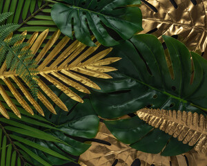 Obraz premium Creative layout with gold and green tropical palm leaves on black background. Minimal summer abstract pattern.