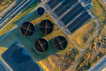 Aerial top down view of sewage treatment plant. Industrial water treatment with round water tanks for sewage recycling from drone view. Waste water management