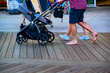 A couple pushes their baby in a carriage along the wooden boardwalk at Ocean City MD.  Mad is...