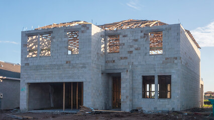 Front of concrete shell of a two-story single-family house under construction in a suburban residential development on a sunny morning in southwest Florida