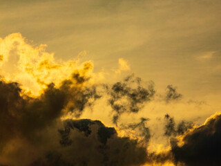 Wispy cloudlets in silhouette, like fragments torn from larger dark clouds nearby, at sunset in May, southwest Florida, for concepts of disruption, release or separation, departure