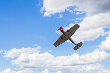 View of an aerobatic plane (aerodyne), in flight under a blue sky with white clouds. flight...