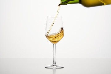 White wine pouring from green bottle, close up shot on white isolated background.
