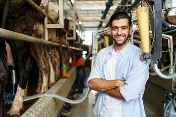 Happy cheerful Middle East - Asian male farmer collecting a dairy milk and smiling to camera.