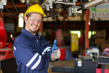 Professional caucasian white ethnicity male technician operating the heavy duty machine in the lathing factory. Technician in safety and helmet suit controlling a machine in factory.