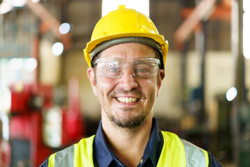 Senior caucasian white ethnicity factory foreman in factory portrait, man in safety suit looking and smiling to camera.