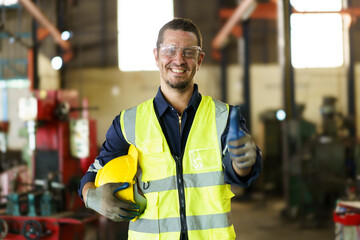 Senior caucasian white ethnicity factory foreman in factory portrait, man in safety suit looking and smiling to camera.
