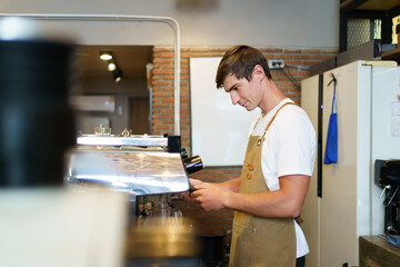 Professional young coffee barista standing inside the counter bar in the coffee shop.