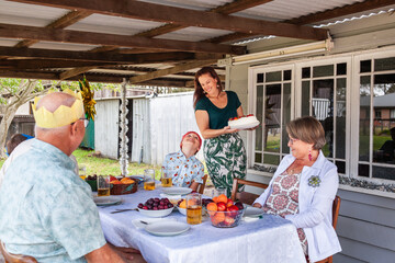 Woman bringing out pavlova for dessert at family Christmas lunch party