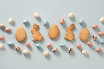 Easter glazed cookies shaped of bunny and chocolate sweets candy as eggs on blue background. View...