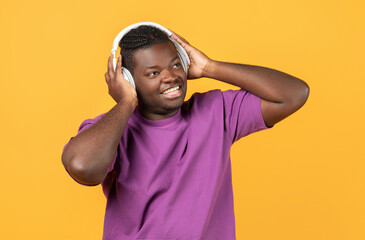 Cheerful Black Man Wearing Wireless Headphones Listens To Song, Studio