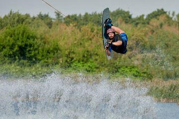 a man on a wakeboard does a reilly trick in a splash water jump - Powered by Adobe