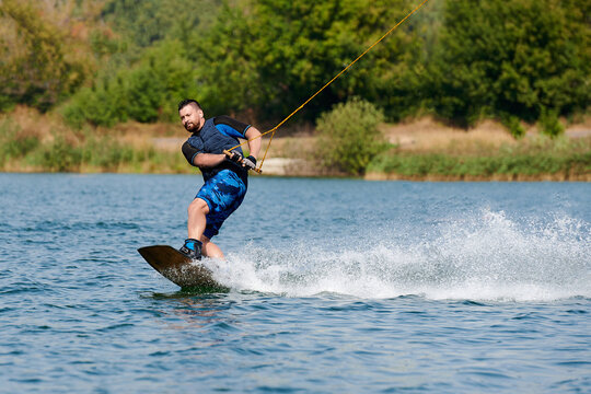 a male wakeboarder rides on water with splashes with a toyside element