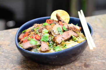 close up view of asian salad nam tok with noodles and beef