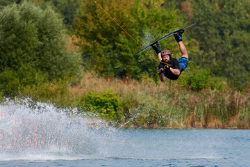 a male wakeboarder does a reilly in a helmet in the water with splashes