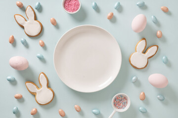 Homemade Easter bunnies shaped cookies and eggs on blue background. Top view. View from above. Festive food and snacks. Greeting card with space for text.
