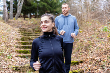 Shot of two young athletes training outdoors. Sporty young couple running together outdoors in the nature.