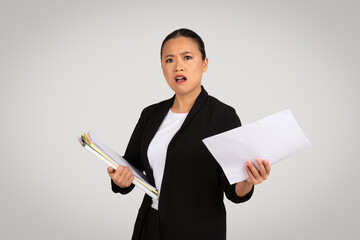Concerned Asian businesswoman holding a clipboard and a document