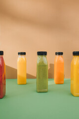 Fruit and vegetable smoothies in transparent plastic bottles. Red, green, orange smoothies on a brown-green background. The concept of healthy eating. Front view