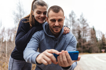 Selfie, fitness and young couple in road after a running exercise for race or marathon training. Happy, sports and young man and woman taking a picture after a cardio workout in outdoor street. - obrazy, fototapety, plakaty