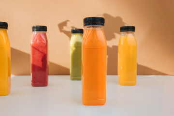 Fruit and vegetable smoothies in transparent plastic bottles. Red, green, orange smoothies on a brown-white background. The concept of healthy eating. Top view