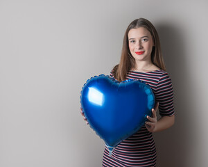 Beautiful young girl with heart shape balloon on bright background. Valentine's Day or love concept.