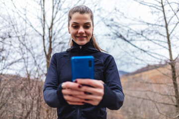 Fototapeta premium Shot of an attractive young woman using her phone while exercising outdoors.