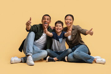 Happy african american family sitting on floor, showing thumb ups