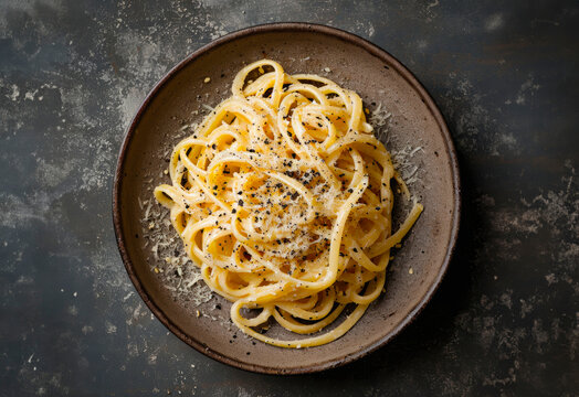 Cacio e Pepe spaghetti on a plate, top view, isolated on a dark marble table
